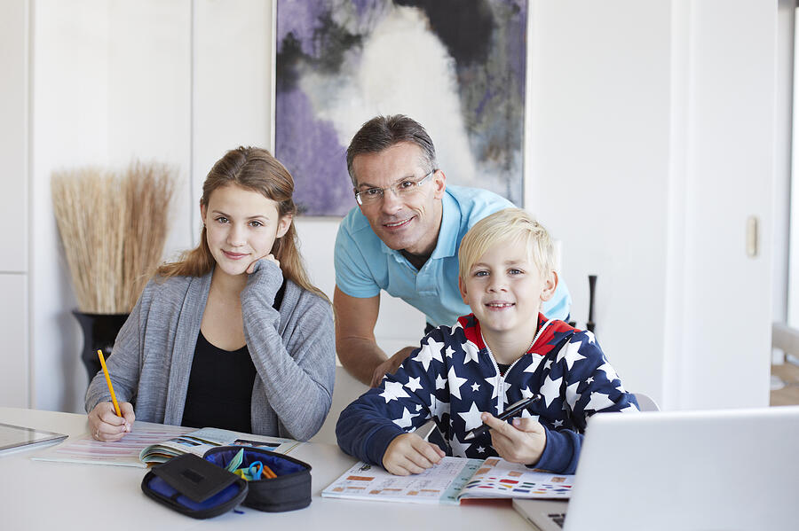 Portrait of father and kids doing homework Photograph by Klaus Vedfelt