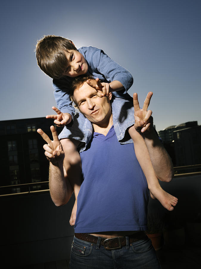 Portrait of father with son (8-9), boy sitting on mans shoulders Photograph by Henrik Sorensen