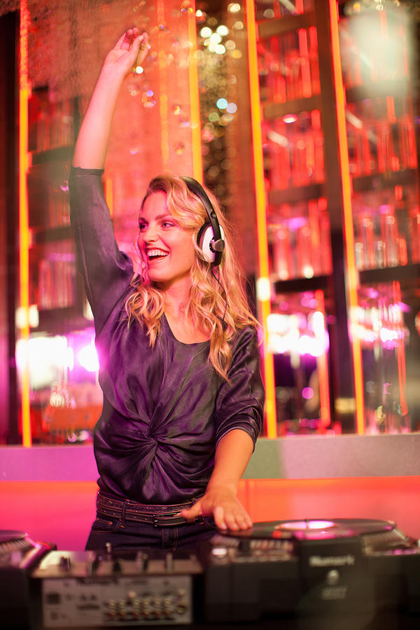 Portrait of female DJ with arms raised in nightclub Photograph by Robert Daly