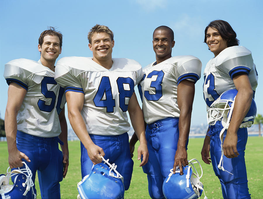 Portrait Of Four Football Players Smiling Photograph by Stockbyte