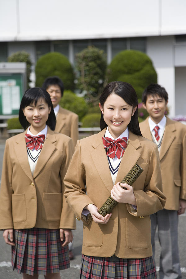 Portrait of four high school students smiling and looking at camera, a girl holding diploma Photograph by Daj