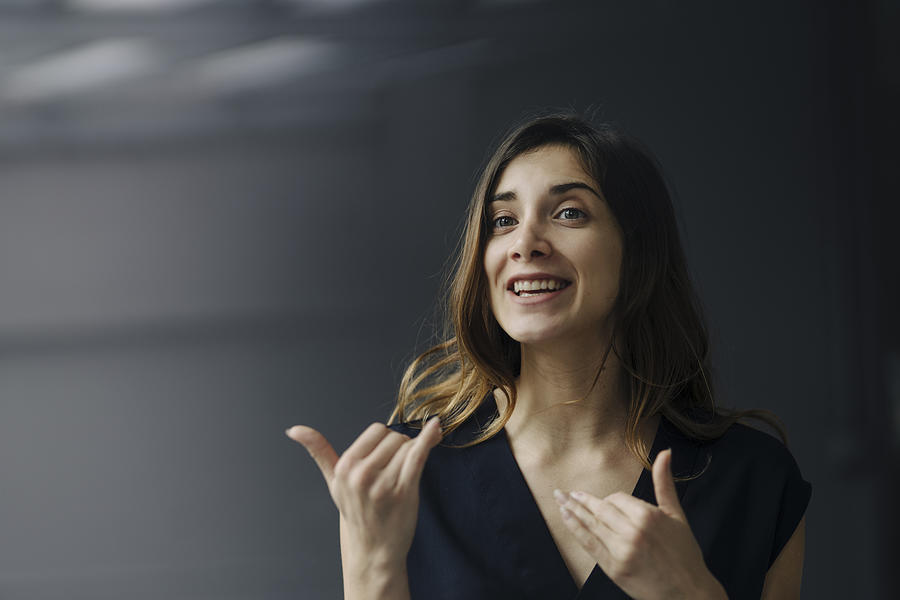 Portrait of gesturing young businesswoman against grey background Photograph by Westend61
