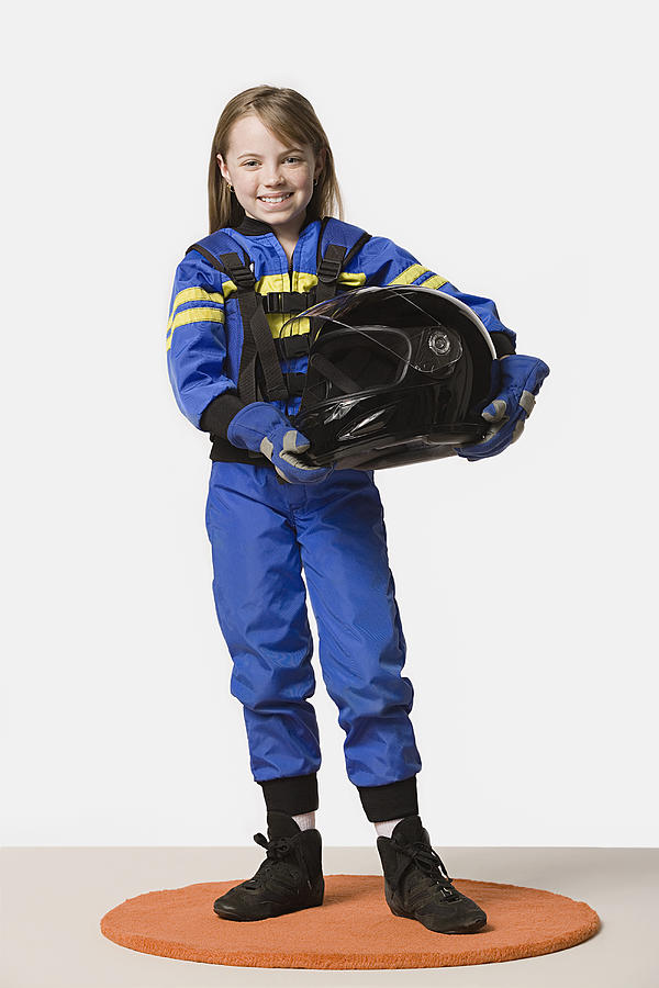 Portrait of girl (8-9) dressed as racing driver, studio shot Photograph by Rob Lewine