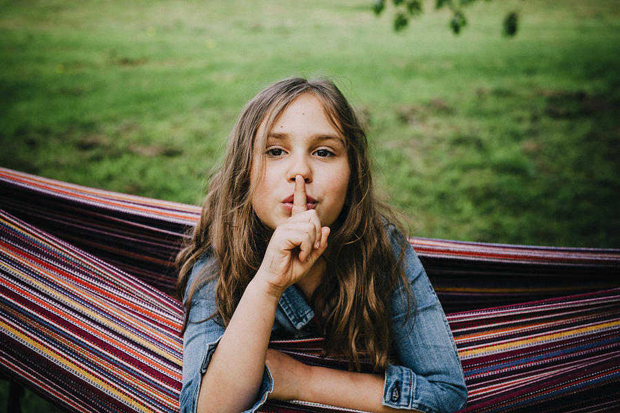 Portrait of girl in hammock with finger on her mouth Photograph by Westend61