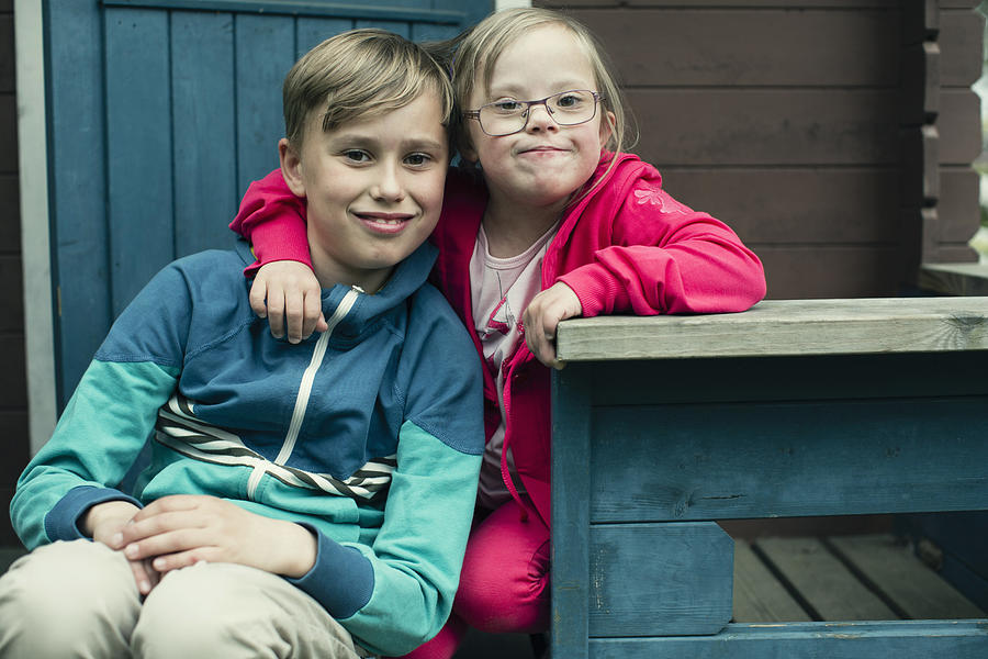 Portrait of handicapped girl with arm around brother sitting on porch Photograph by Maskot