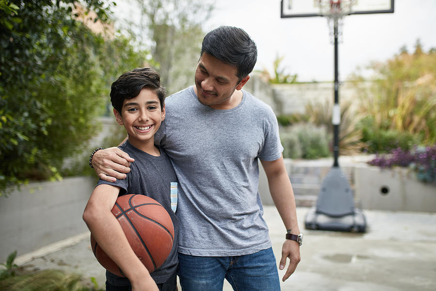 Portrait of happy boy and father with basketball Photograph by Xavierarnau
