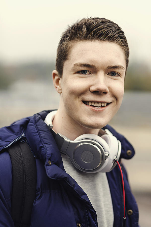 Portrait of happy male university student with headphones around neck outdoors Photograph by Maskot
