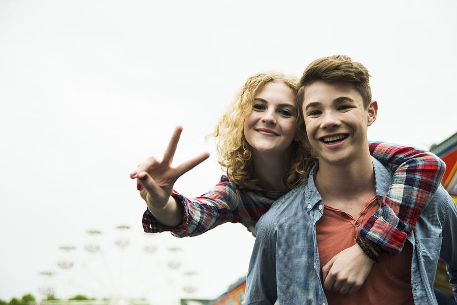 Portrait of happy teenage couple showing victory-sign Photograph by Westend61