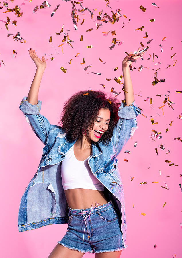 Portrait of happy young afro woman among confetti Photograph by Izusek