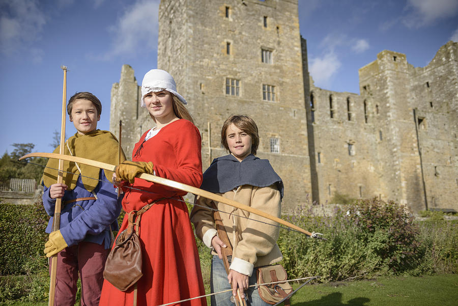 Portrait of history students in period dress with longbows and crossbow outside Bolton Castle, a 14th century Grade 1 listed building, Scheduled Ancient Monument Photograph by Monty Rakusen