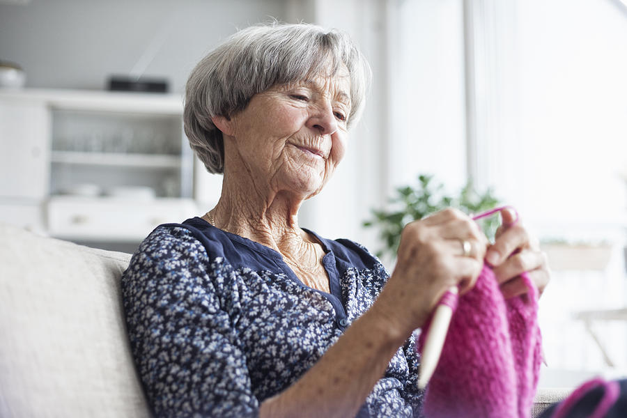 Portrait of knitting senior woman sitting on couch at home Photograph by Westend61