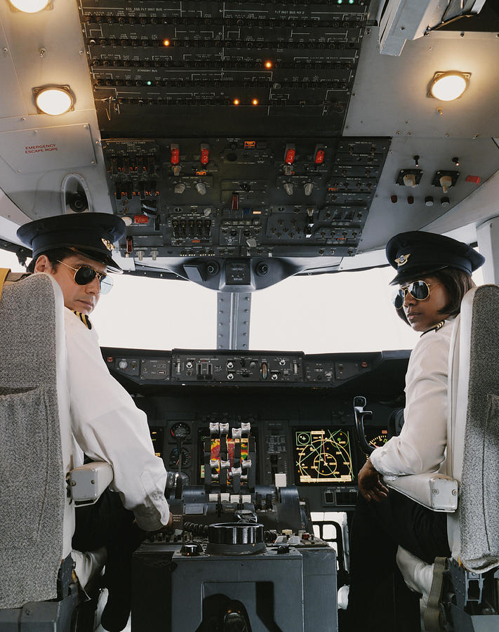 Portrait of Male and Female Pilots Sitting in the Cockpit Photograph by Digital Vision.
