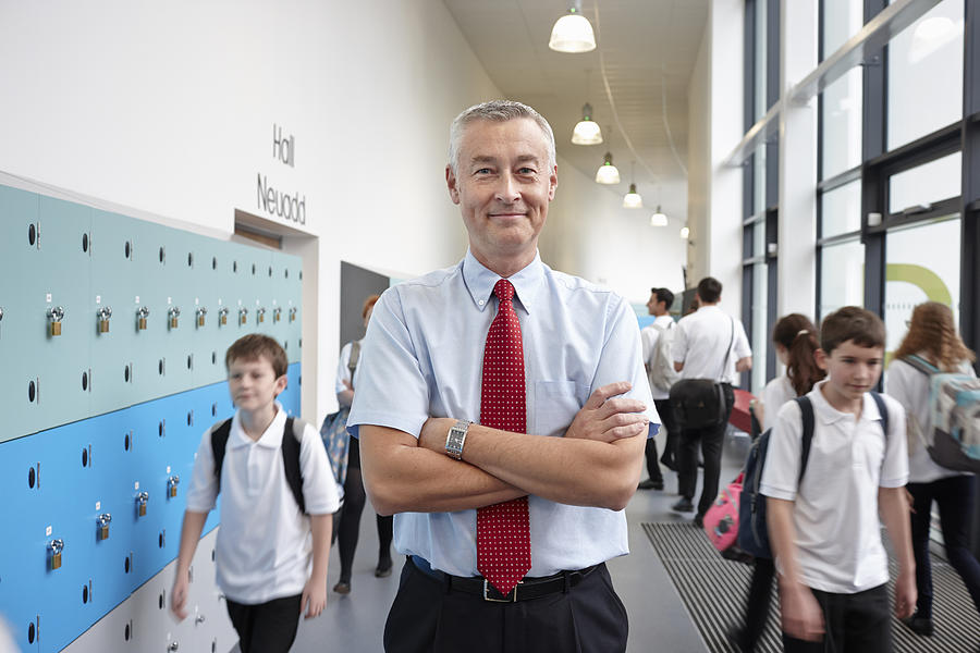 Portrait of male teacher with arms folded in school corridor Photograph by Phil Boorman