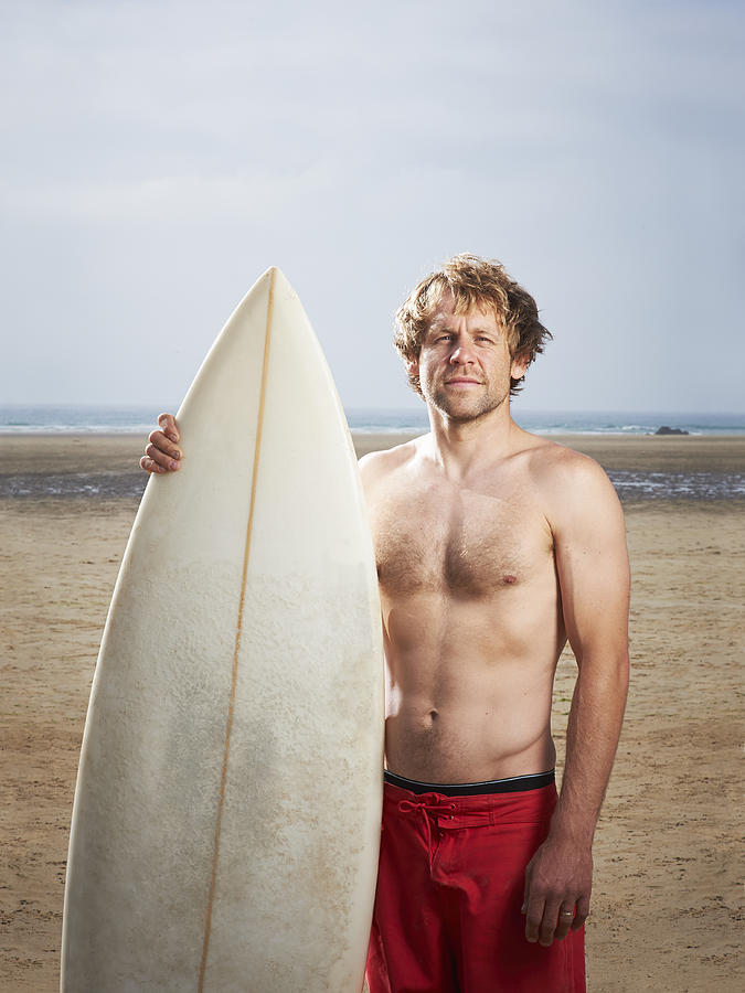 Portrait of man at beach with surfboard. Photograph by Dougal Waters