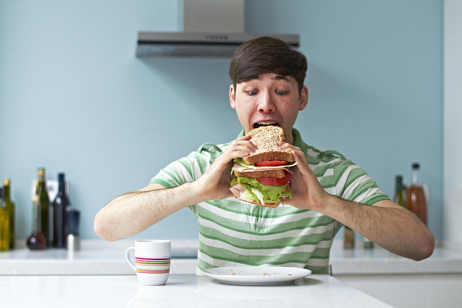 Portrait of man eating giant sandwich Photograph by Flashpop