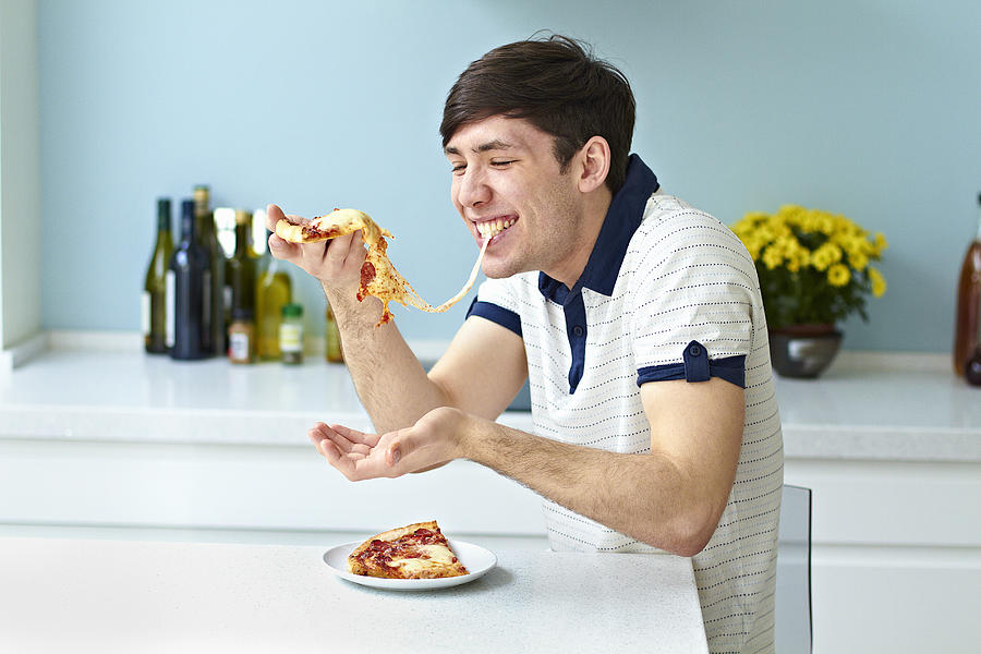 Portrait of man eating pizza Photograph by Flashpop