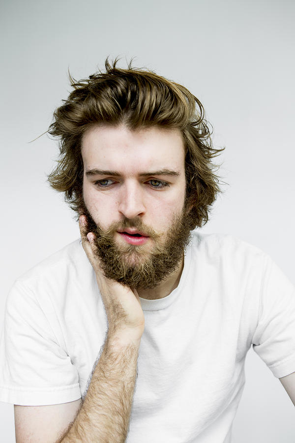 Portrait of man rubbing beard Photograph by Catherine Ledner