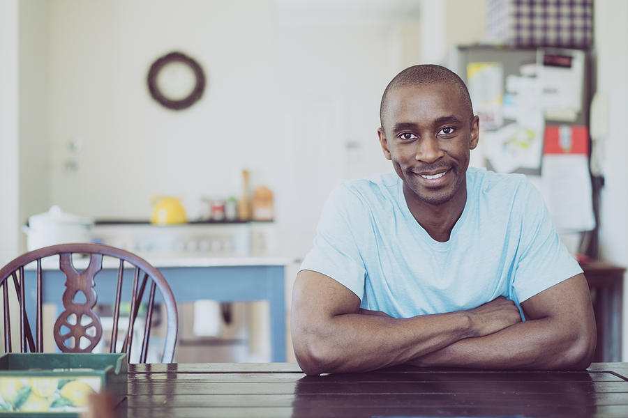 Portrait of man smiling at table in kitchen Photograph by Portra