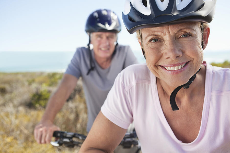 Portrait of mature woman in sports helmet smiling with man in background Photograph by OJO Images