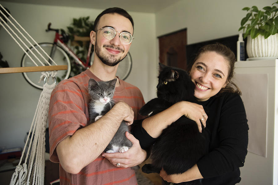 Portrait of millennial couple and newly adopted kitten at home. Photograph by Martinedoucet