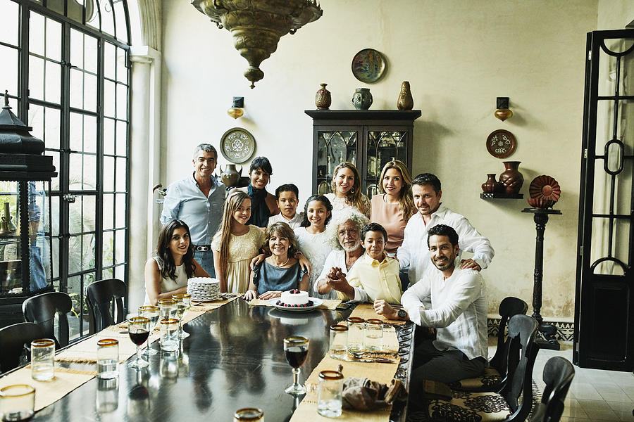 Portrait of multigenerational family gathered at dining room table for birthday dinner Photograph by Thomas Barwick