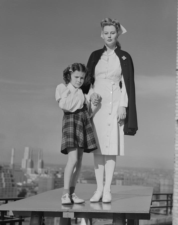Portrait of nurse with girl on table, cityscape in background Photograph by George Marks