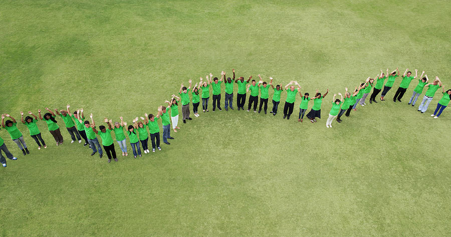 Portrait of people in green t-shirts forming wavy line in field Photograph by Martin Barraud