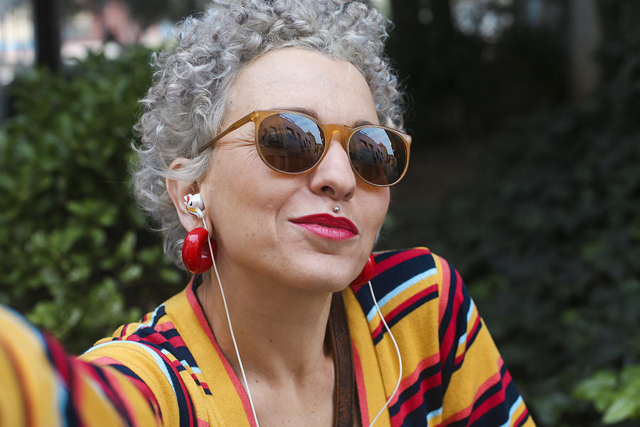 Portrait of pierced mature woman wearing sunglasses and earphones Photograph by Westend61