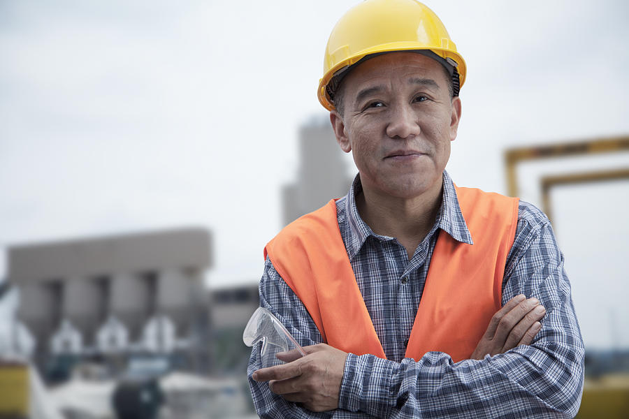 Portrait of proud worker with arms crossed in protective workwear outside of a factory Photograph by XiXinXing