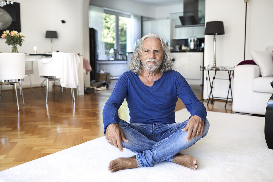 Portrait of senior man sitting on the floor at home Photograph by Oliver Rossi