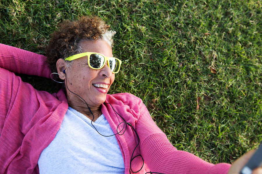 Portrait of senior woman lying on grass wearing sunglasses Photograph by David Jakle