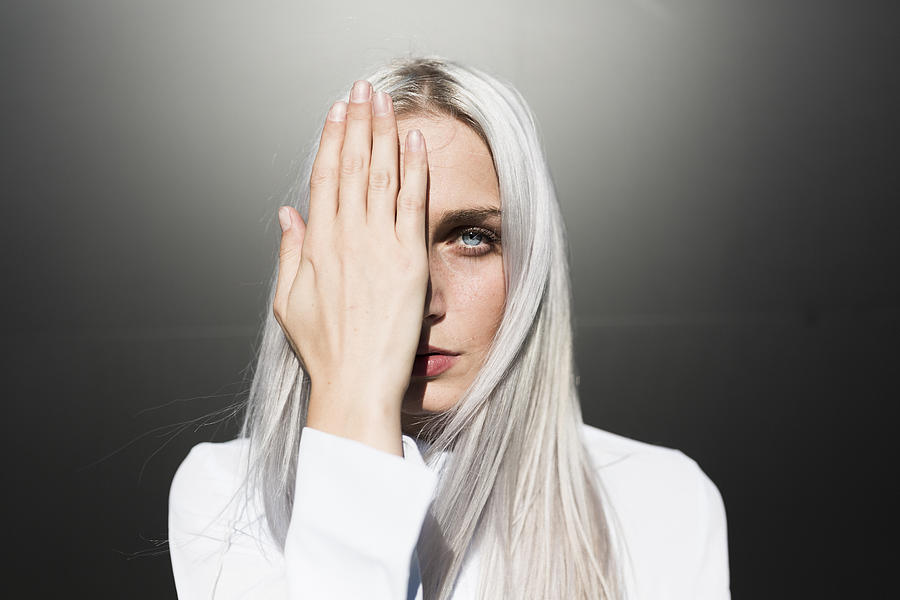 Portrait of serious young woman covering one eye Photograph by Westend61