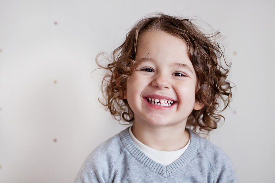 Portrait of smiling boy with curly brown hair Photograph by Daniela Solomon