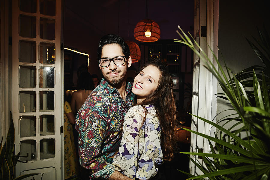 Portrait of smiling embracing couple on date in night club Photograph by Thomas Barwick