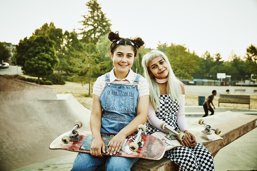 Portrait of smiling friends sitting on ramp in skate park on summer morning Photograph by Thomas Barwick