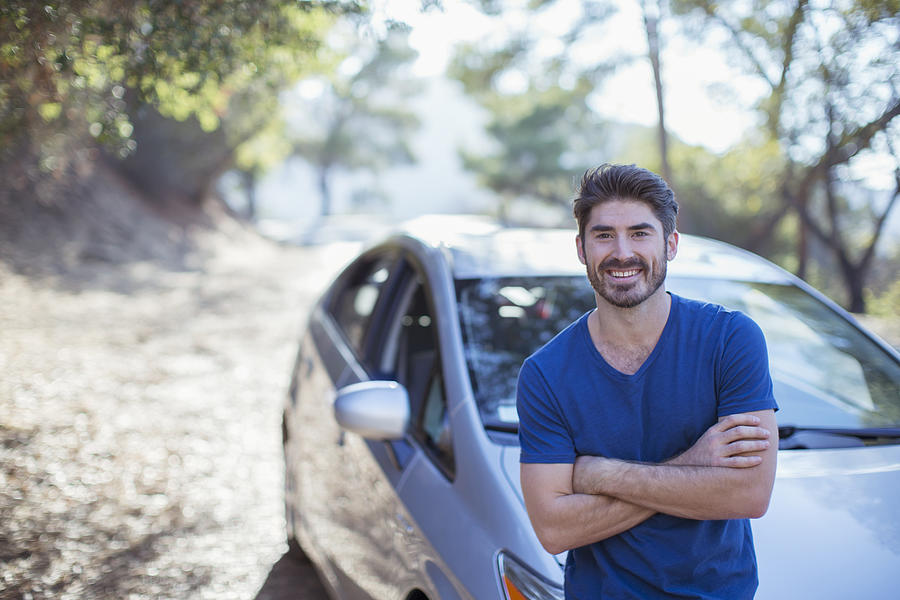 Portrait of smiling man leaning on car Photograph by Caia Image