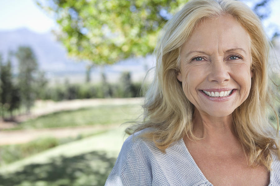 Portrait of smiling mature woman in park Photograph by OJO Images