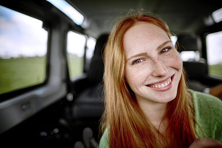 Portrait of smiling redheaded young woman in car Photograph by Oliver Rossi