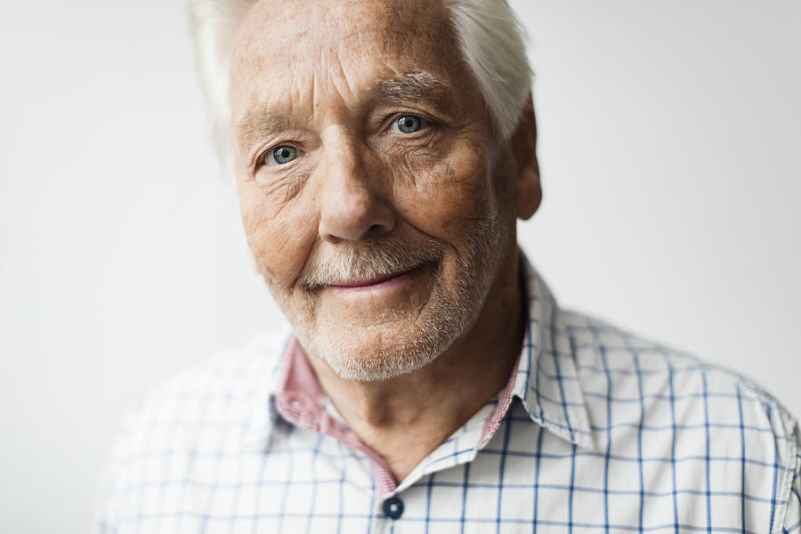 Portrait of smiling senior man against white background Photograph by Maskot