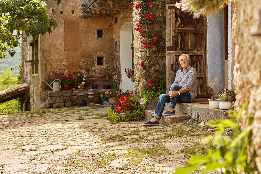 Portrait of smiling senior man sitting on porch Photograph by Morsa Images