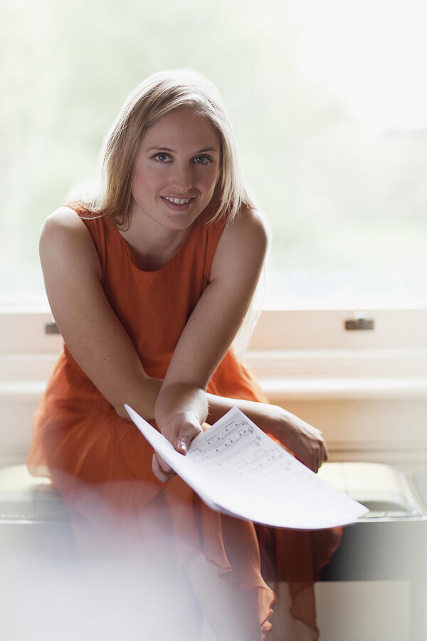 Portrait of smiling woman holding sheet music near window Photograph by Sam Edwards