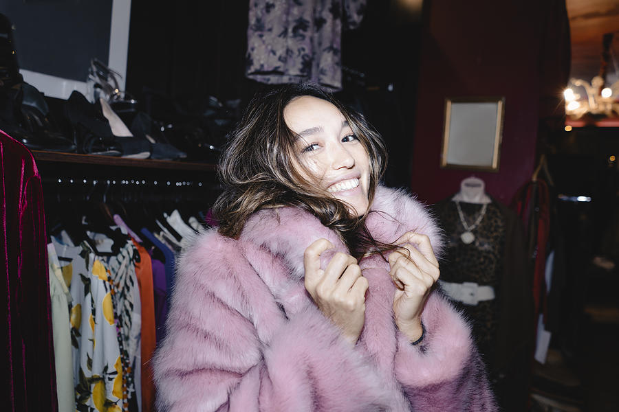 Portrait of smiling woman wearing pink fur jacket at thrift store Photograph by Westend61