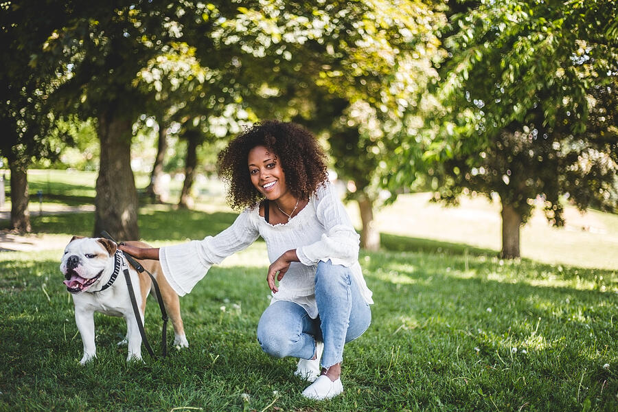 Portrait of smiling woman with bulldog on grassy field at park Photograph by Maskot