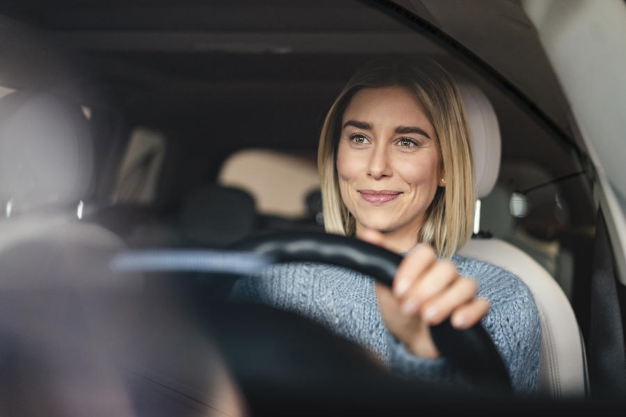 Portrait of smiling young woman driving a car Photograph by Westend61