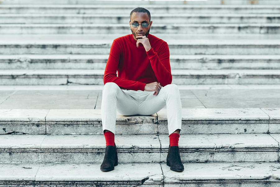 Portrait of stylish young man wearing red pullover and socks sitting on stairs Photograph by Westend61