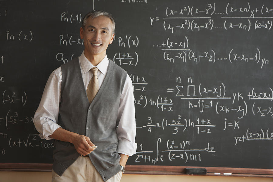 Portrait of teacher with in front of blackboard Photograph by SelectStock