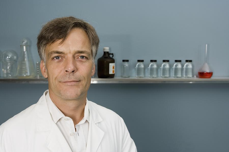 Portrait of technician or doctor with specimen bottles in background Photograph by fStop Images