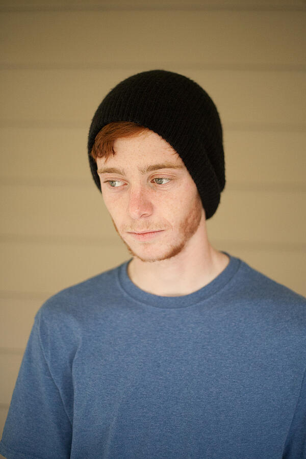 Portrait of teenage boy in beanie hat looking sideways Photograph by Heshphoto