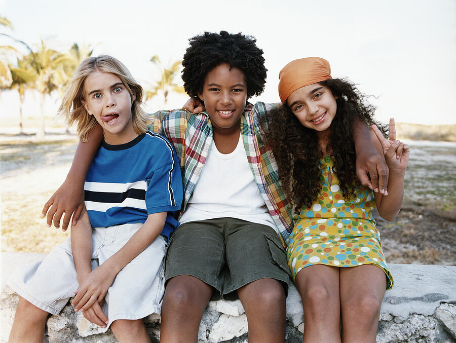 Portrait of Three Young Friends Sitting Together on a Stone Wall Photograph by Digital Vision.