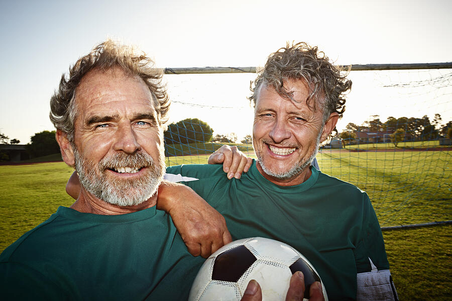 Portrait of two mature soccer players smiling Photograph by Uwe Krejci